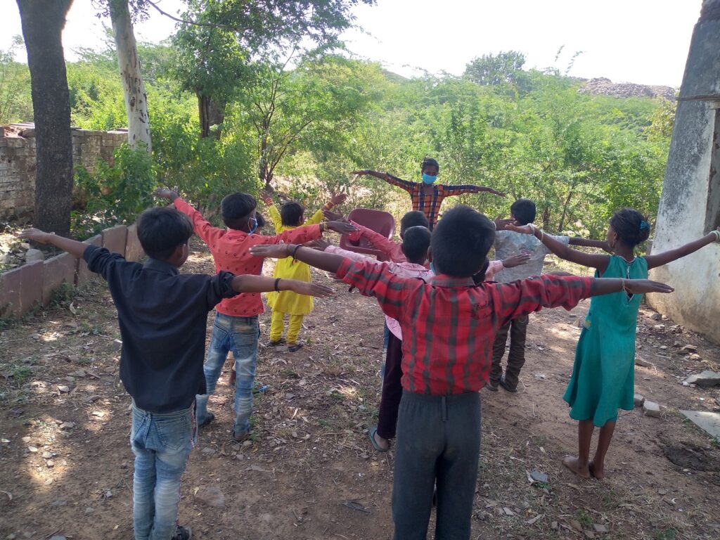 An adolescent girl wearing a surgical mask because of Covid restrictions, leads a warm up session in the open air, before classes begin, in Budhpura, Rajasthan, India